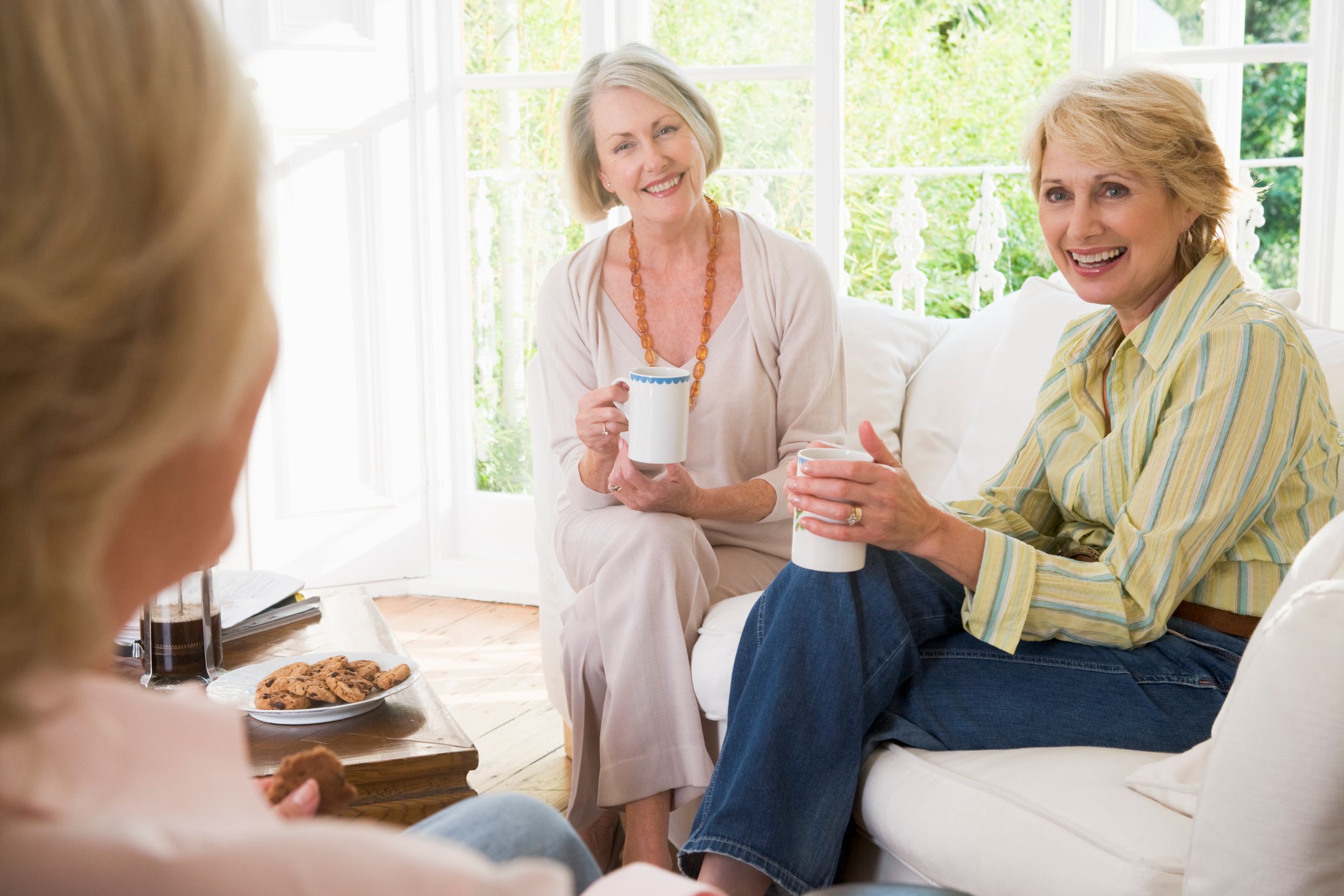 three-women-in-living-room-with-coffee-smiling_BFkxPu5Cri
